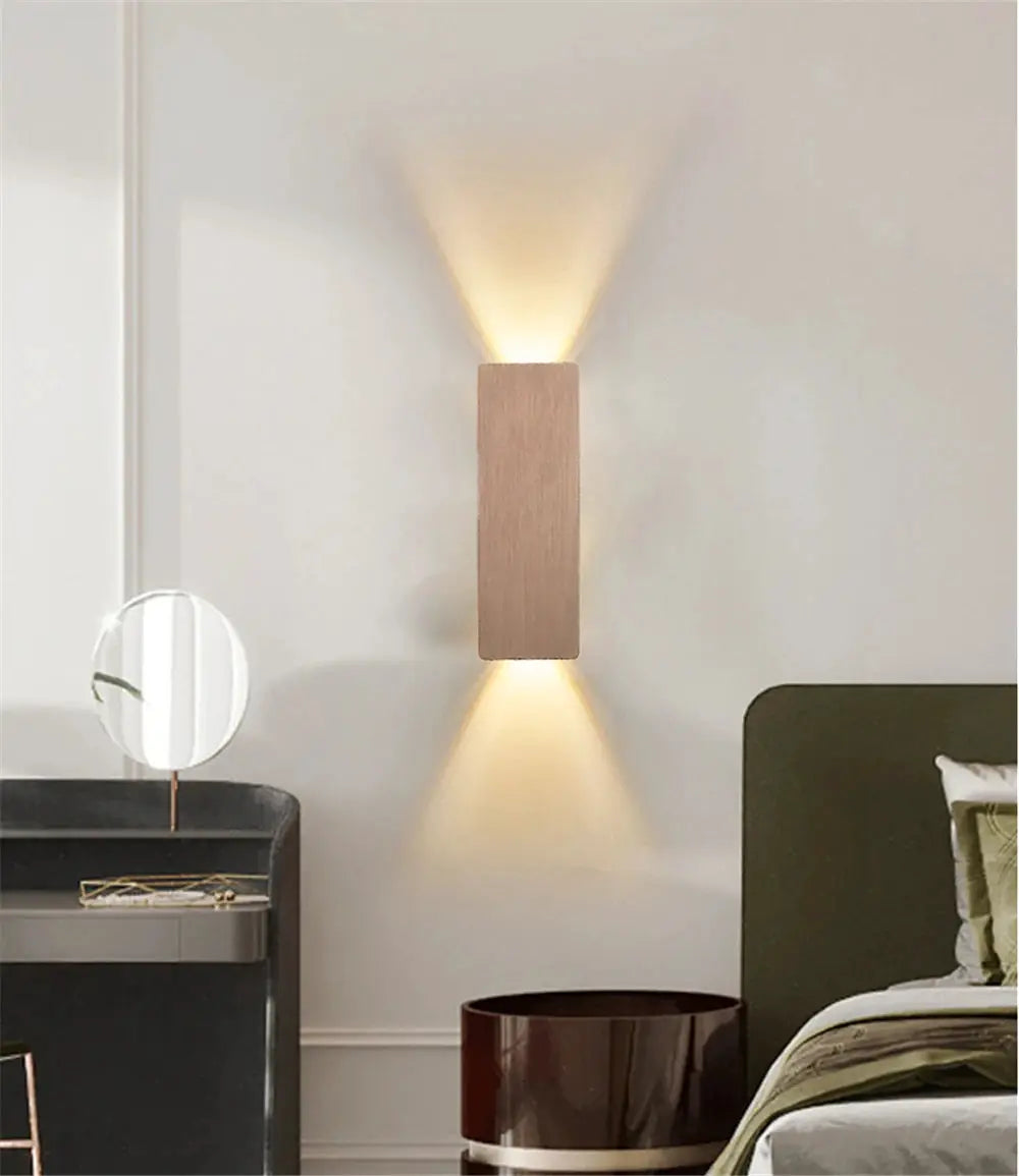 Modern LED wall lamp with a wood-finish rectangular block, emits warm uplight and downlight for bedroom or living room.