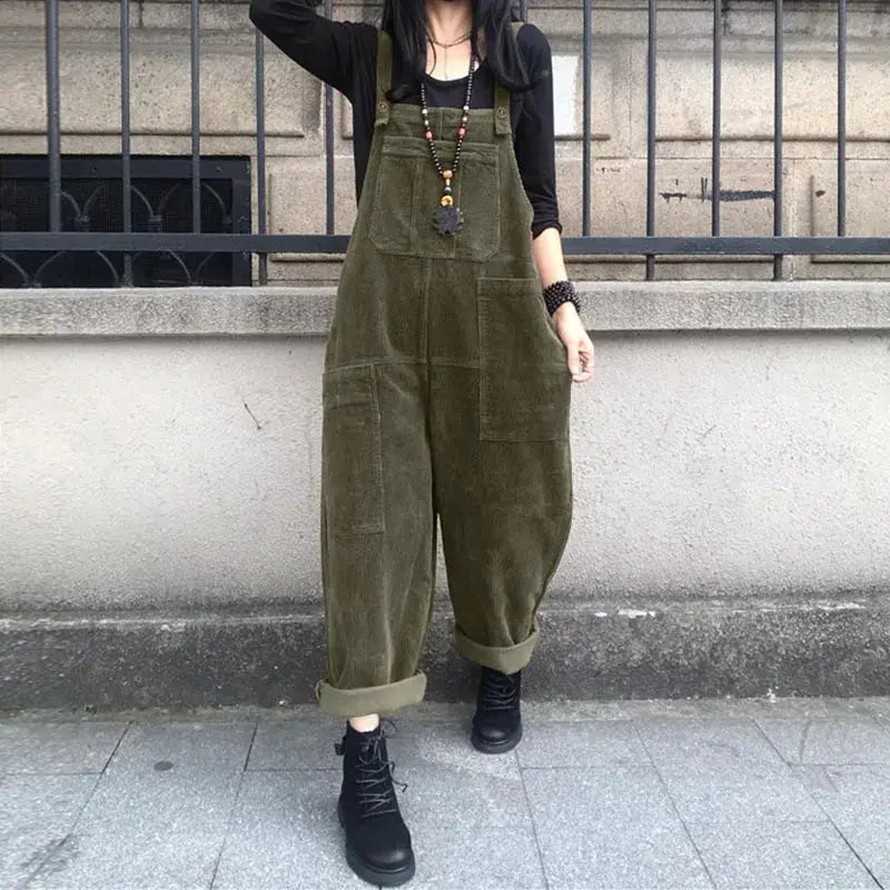 Olive green corduroy overalls with front pockets and rolled cuffs worn over a black top.