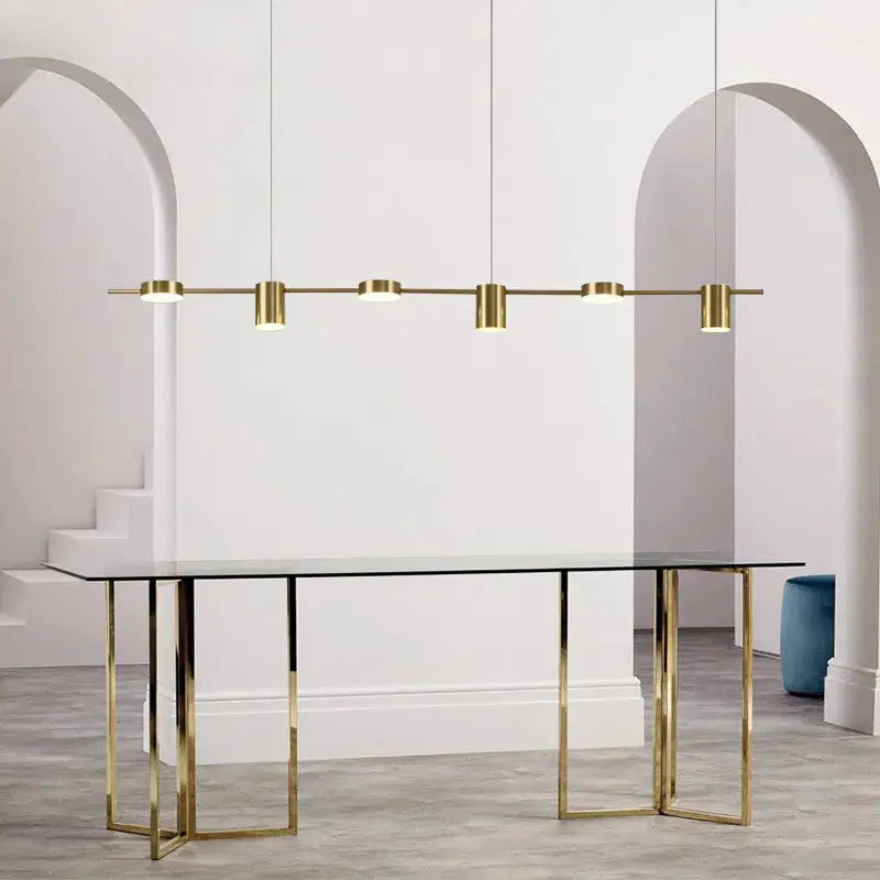 Modern LED linear chandelier with brass finish over a glass dining table, featuring bar-mounted multi-lamp design.