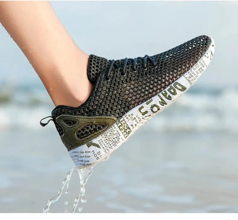 Black mesh water shoe with white printed foam sole, worn on foot at the beach.