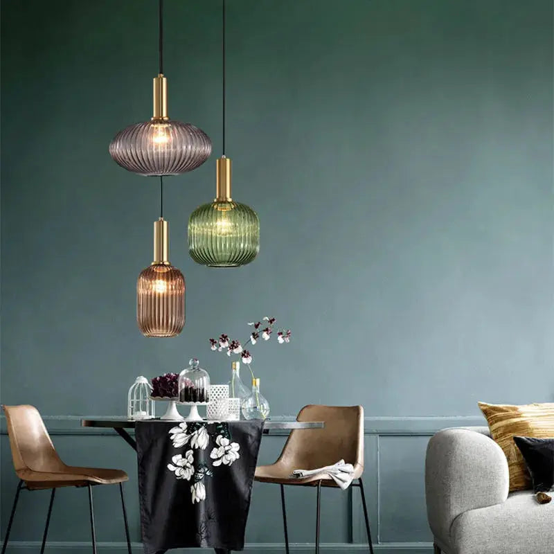 Retro glass pendant lights, set of three in purple, amber and green with brass fittings above dining table.