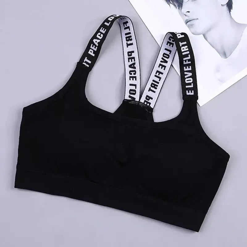 Black women's sports bra top with wide band and dual back straps featuring white text.