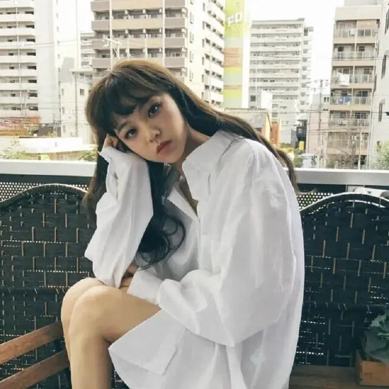Oversize white shirt blouse on model with long sleeves; minimalist chic style.