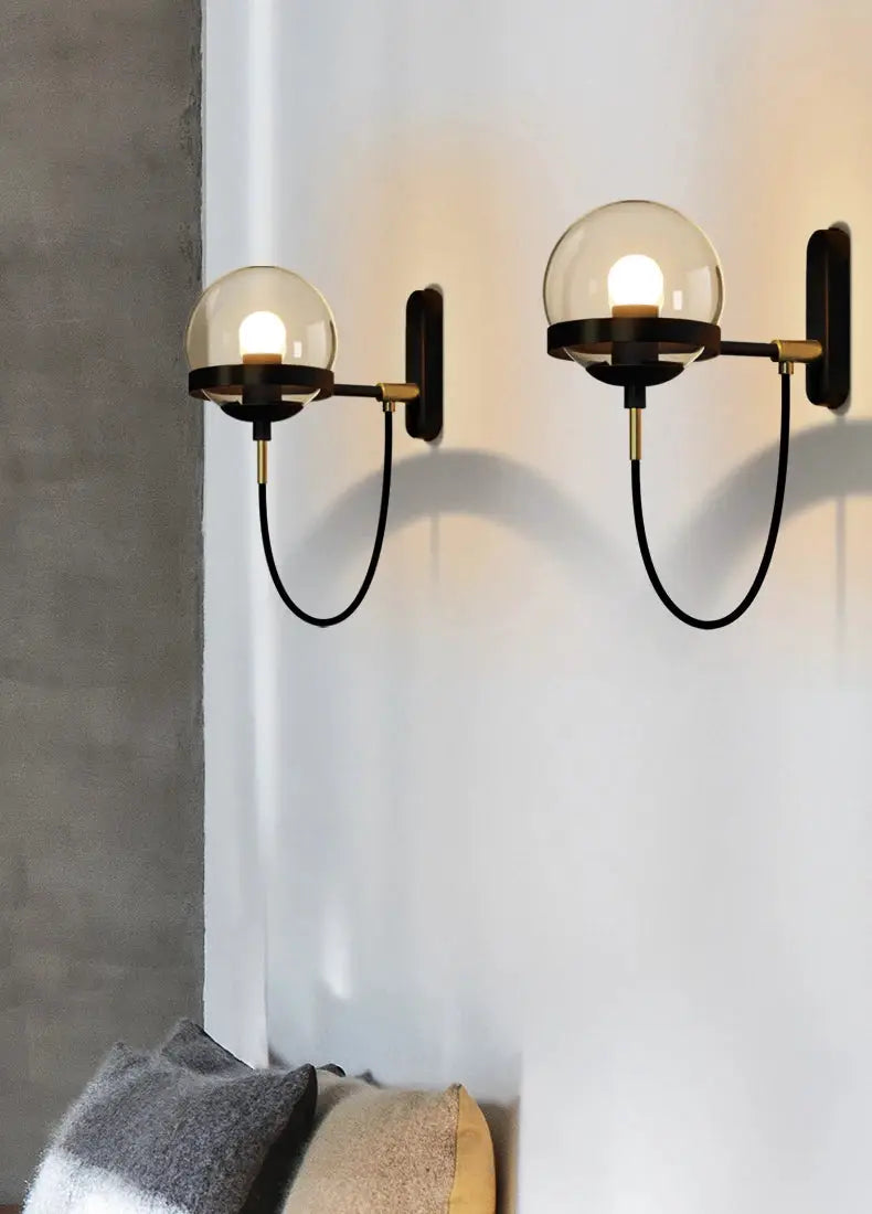 Modern glass ball wall lamps, pair with clear glass globes and black-brass finish.