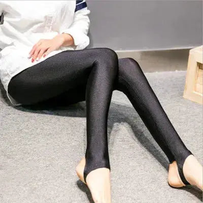 Women's shiny black full-length leggings worn by a seated model in a white top