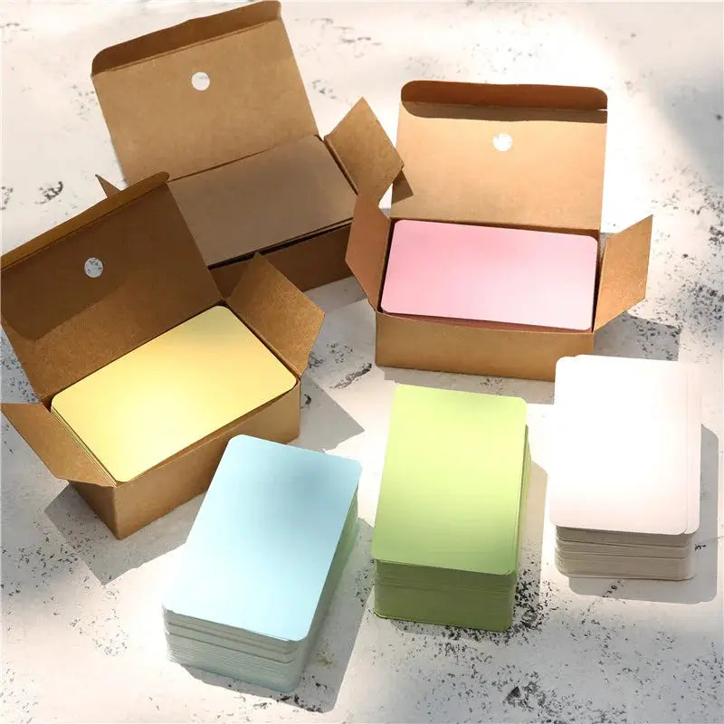 Blank kraft paper cards in pastel colors; 100 pcs per box, shown in open boxes with pink, blue, yellow and green stacks.