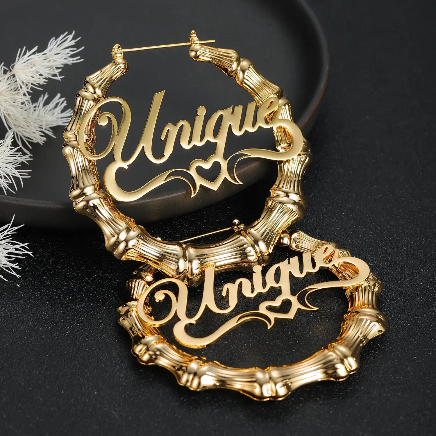 Pair of gold-tone bamboo hoop earrings with script name cutout design.