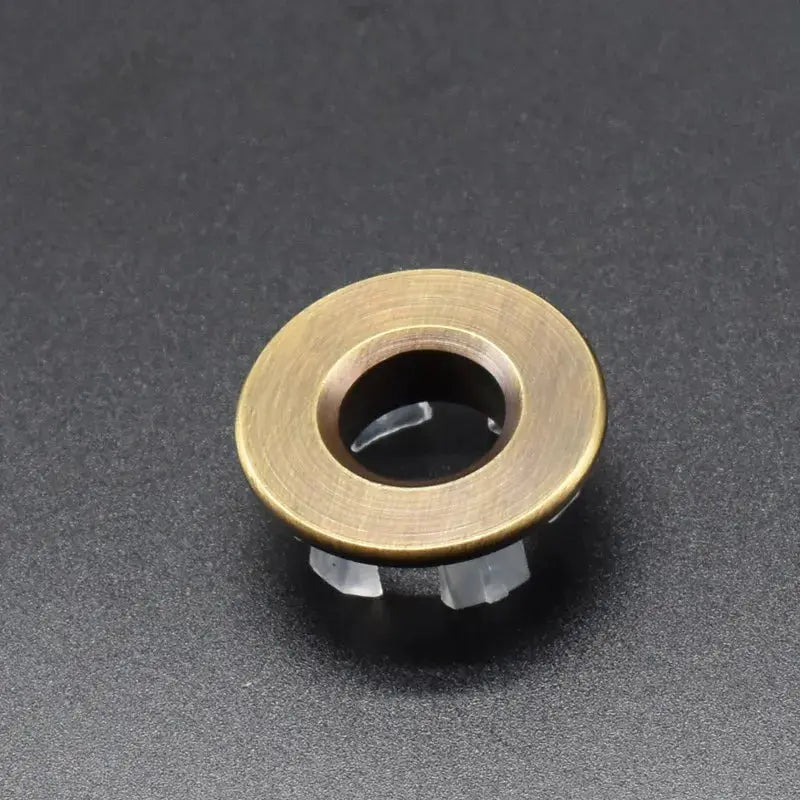 Overflow hole decorative cover for sink, brass copper-tone ring with black center, Simples Market.