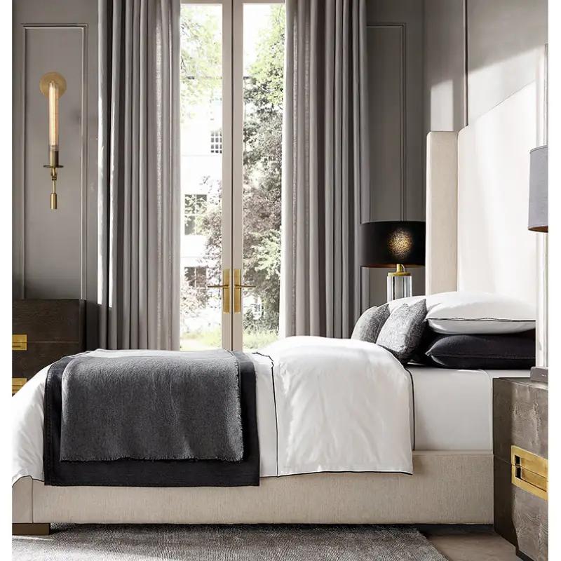 Modern copper wall sconce lamp with round backplate and vertical bulb on gray wall in a contemporary bedroom