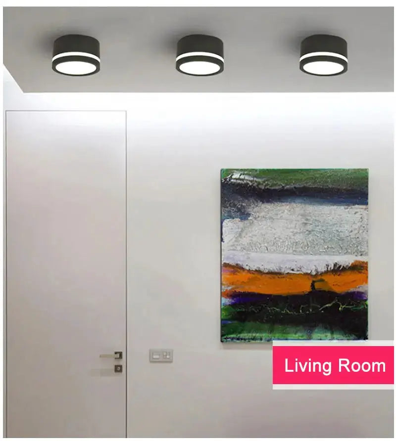 Three black round LED surface-mounted downlights installed on a ceiling