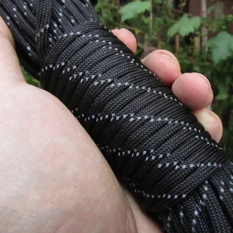 Reflective paracord rope, black 4mm 7‑strand cord with white reflective threads, held in hand