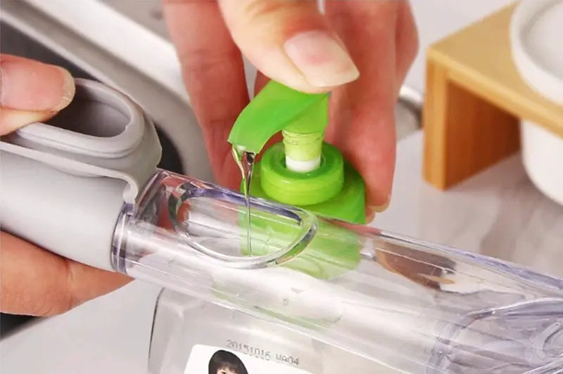 Refillable liquid cleaning brush by Simples Market with long handle and green soap dispenser.