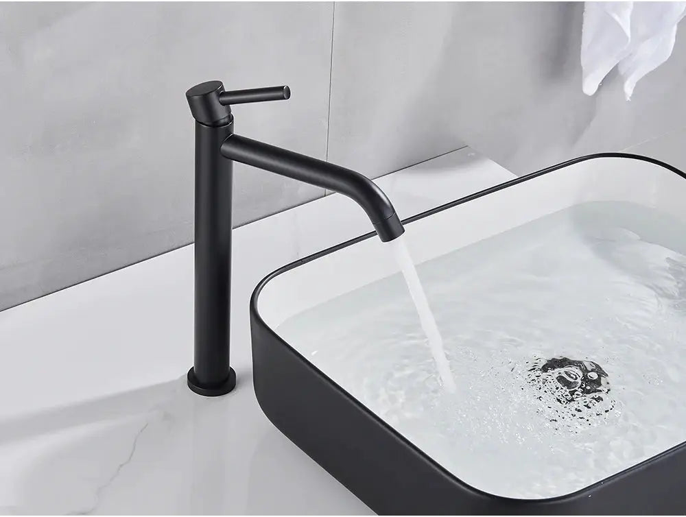 Simples Market black matte basin faucet with tall column and curved spout over a white washbasin