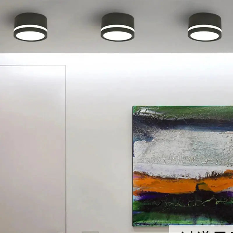 Three black LED surface-mounted downlights with white ring illumination on the ceiling.