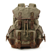 Vintage canvas backpack with brown leather straps and brass hardware, waxed olive canvas for travel.