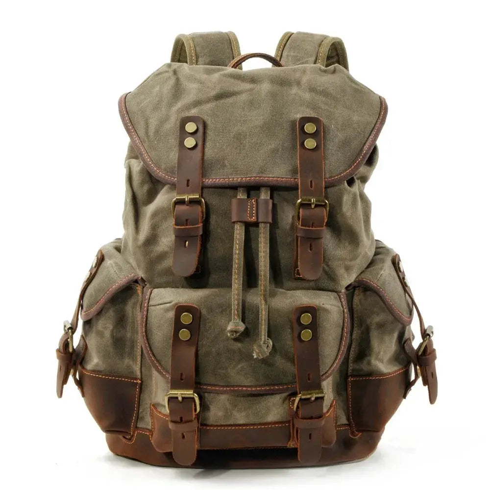 Vintage canvas backpack with brown leather straps and brass hardware, waxed olive canvas for travel.