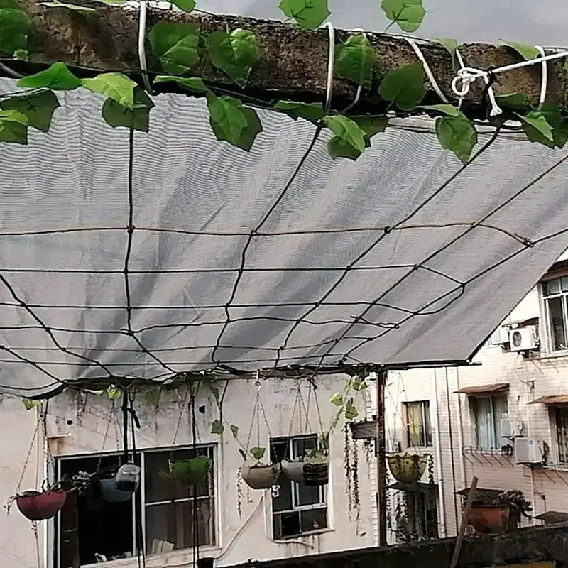 HDPE sun shade net canopy over a balcony garden with hanging pots and climbing vines