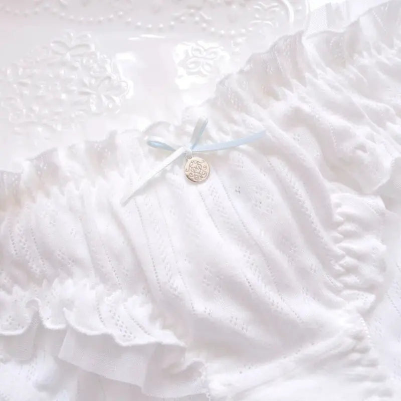 Panties by Simples Market, white lace with ruffles and a light blue bow with a round metal charm.