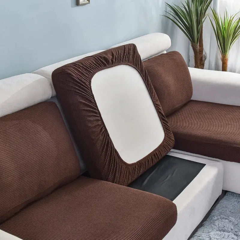 Sofa cushion slipcovers in brown stretch fabric on a white sectional, removable and washable.