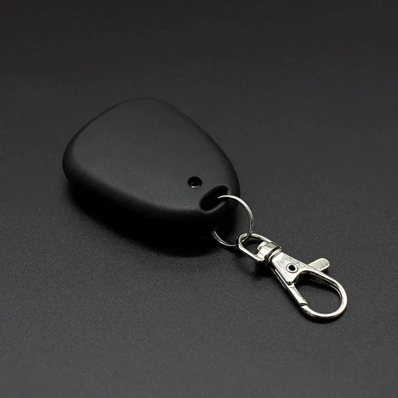 Black teardrop-shaped garage door remote with silver keyring and metal clip
