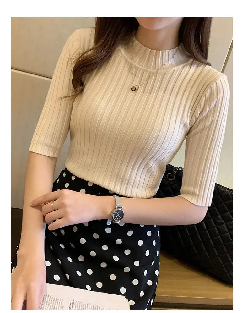Beige ribbed knit mock-neck blouse for women, shown with a black polka-dot skirt.