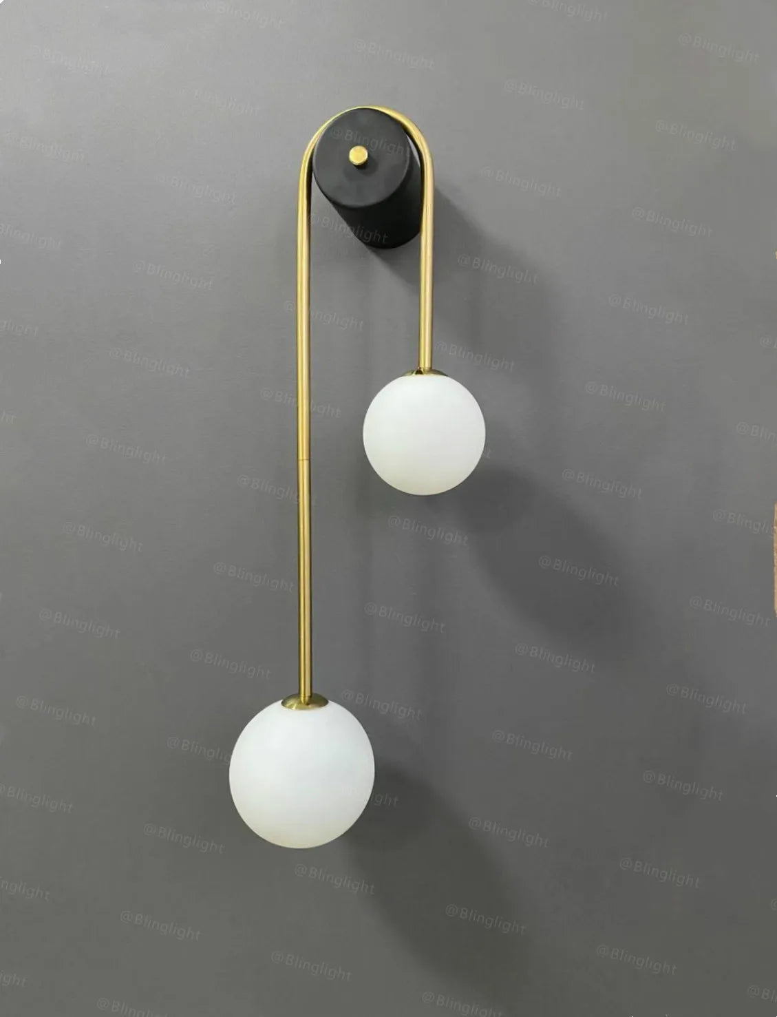 Modern wall lamp with a gold curved arm and dual white glass globe shades LED