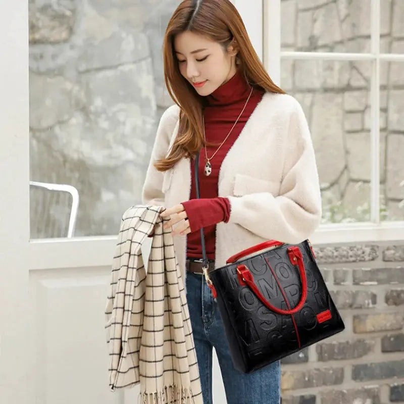 PU Leather Casual Crossbody Bag in black with red handles and embossed pattern, carried by a woman.