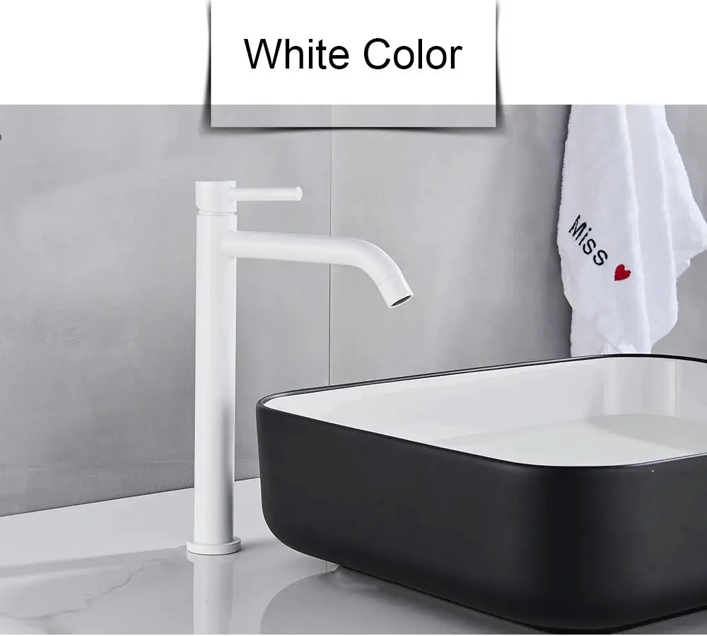 White bathroom basin faucet with tall column and single lever beside a black-and-white basin sink