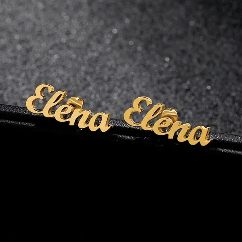 Gold-tone stainless steel pair of personalized name earrings spelling Elena in cursive nameplate studs