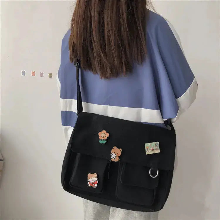 Women's messenger bag in black with decorative patches, front pockets and crossbody strap