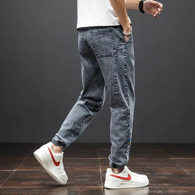 Men's grey washed denim cargo jogger pants with elastic cuffs and multiple cargo pockets, streetwear style.