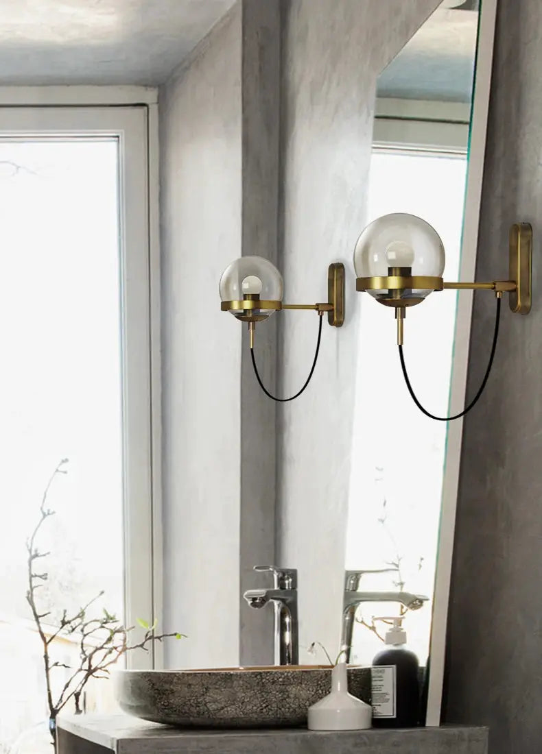 Modern glass ball wall lamp pair by Simples Market in brass finish with two globe bulbs