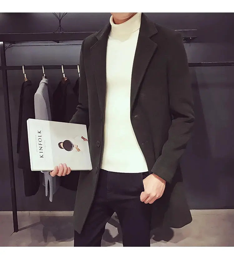 Long men's wool-blend coat in dark green, worn over a cream turtleneck and black pants