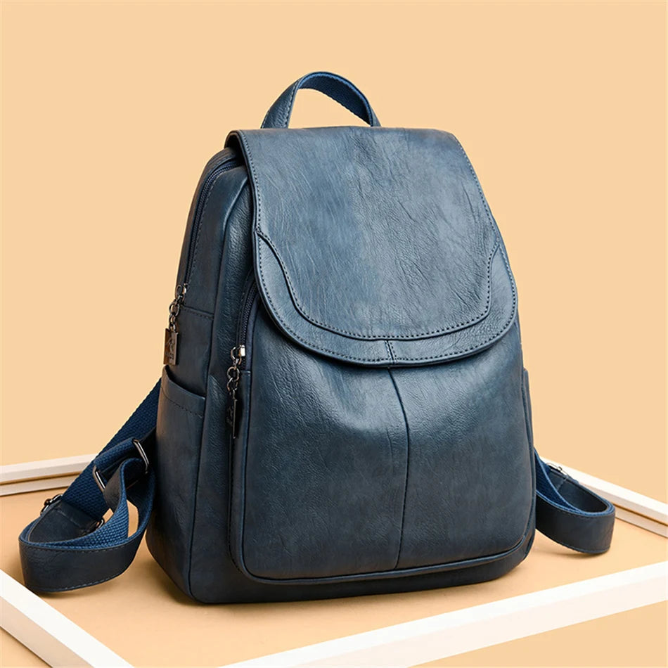 Backpack by Simples Market in blue genuine leather with flap front, top handle and adjustable straps.