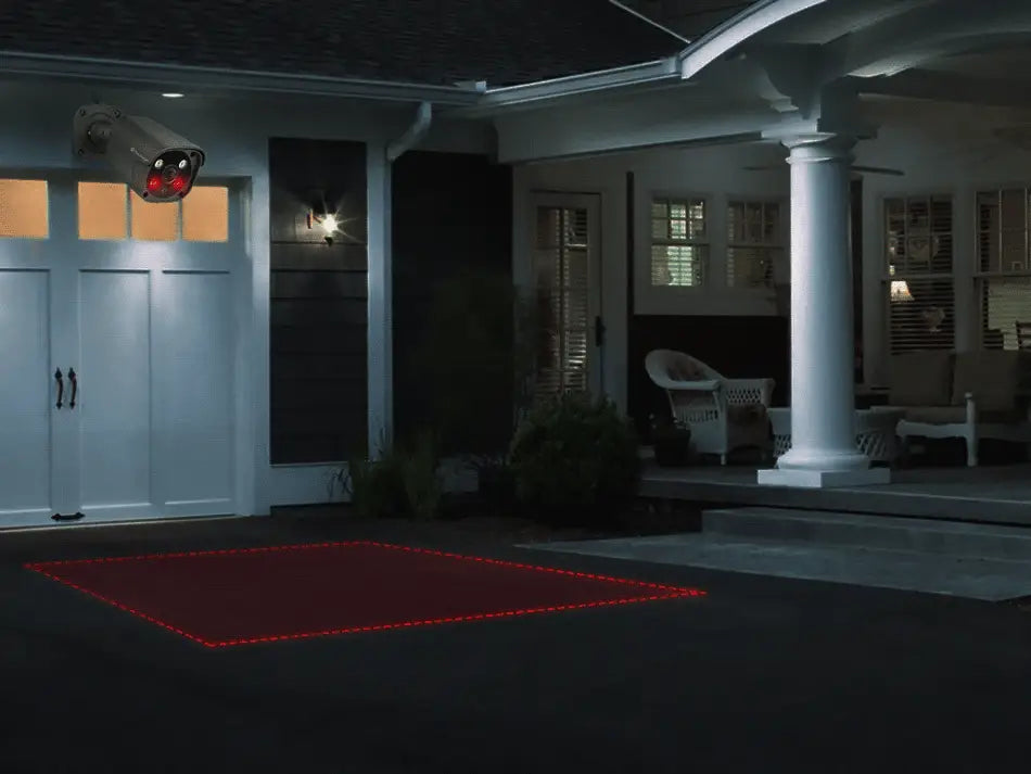 Outdoor metal IP security camera mounted on house by driveway with red LED illumination