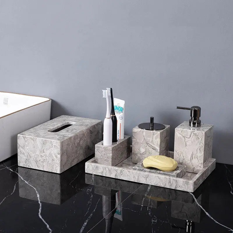 Natural marble bathroom accessories set by Simples Market with soap dispenser, toothbrush holder, cup and soap dish.