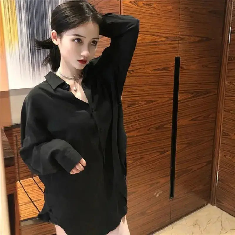 Oversize black women's shirt with long sleeves and button-up front, worn by model.