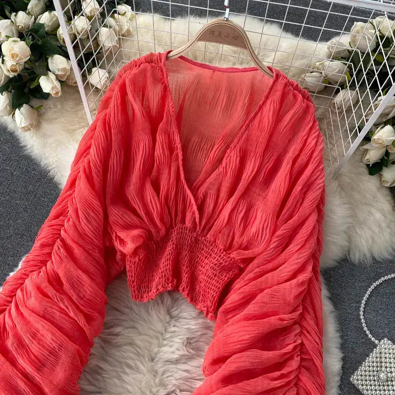 Draped chiffon blouse for women in coral red with V-neck, puff long sleeves, and cropped smocked waist.