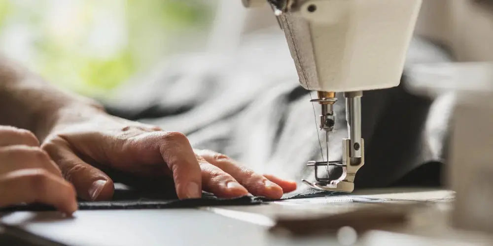 Men's suit vest being sewn on a sewing machine; black jacquard fabric.