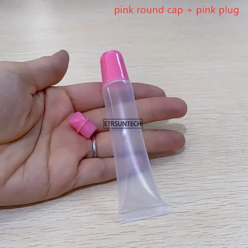 Clear lip gloss container with pink round cap, empty squeeze tube held in hand