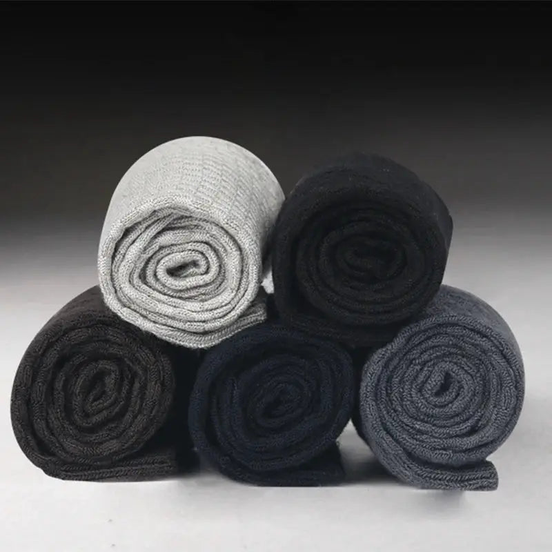 Five rolled men's bamboo fiber compression dress socks in black, gray, and navy tones, displayed as a color assortment.