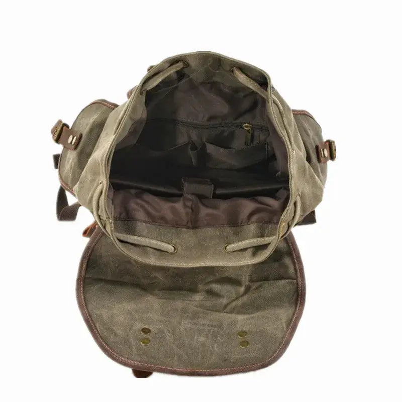 Vintage canvas backpack with flap open, olive waxed canvas, brown leather straps, interior pocket