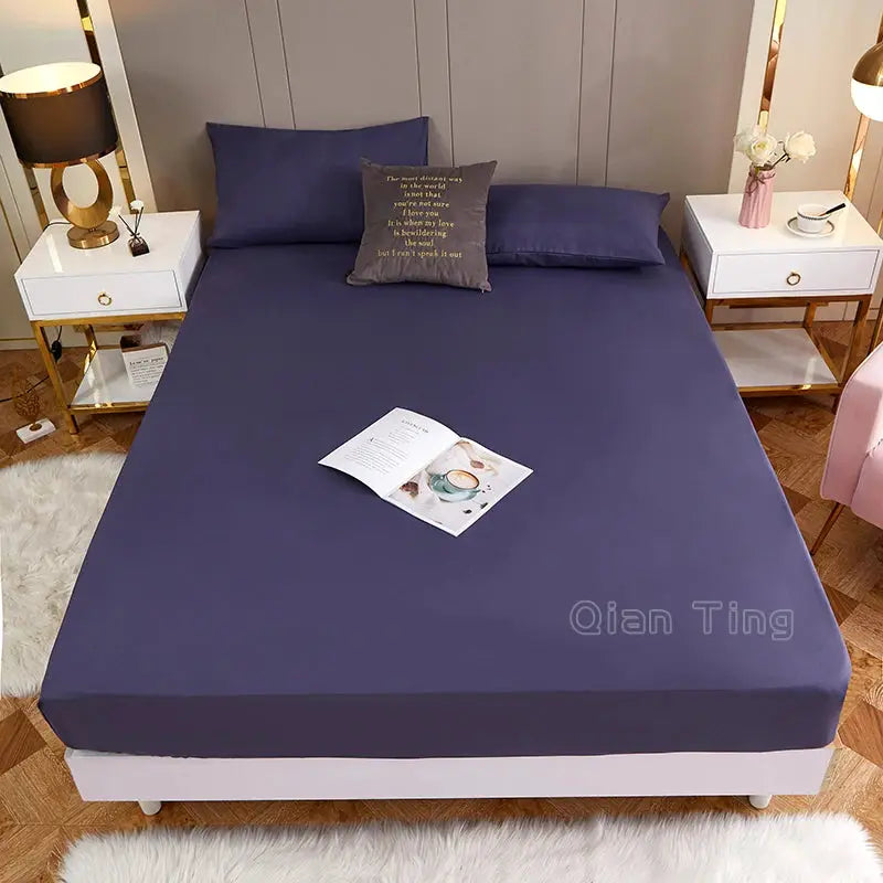 Fitted bed sheet in navy blue polyester with elastic edges on a white bed