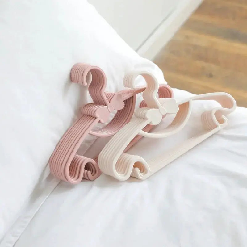 Plastic baby clothes hangers set in pastel pink and ivory for organizing children's outfits