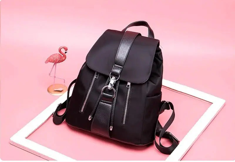Women's black nylon backpack with leather accents, front zip pockets and top flap