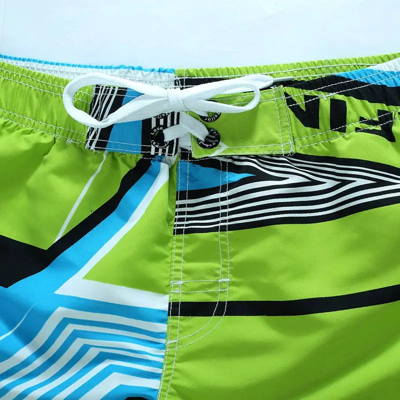Men's surf board shorts in lime green with blue geometric print and white drawstring.