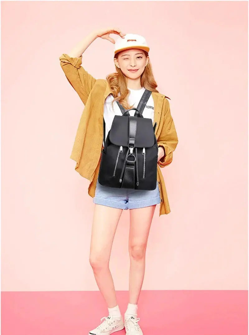 Women’s black nylon backpack with front flap and silver zippers, large capacity