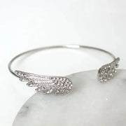 Adjustable silver angel wings bracelet for women with crystal accents, open cuff feather design.