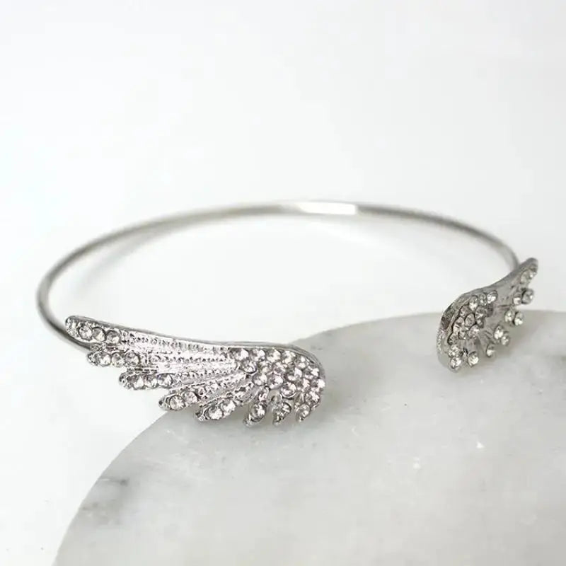 Adjustable silver angel wings bracelet for women with crystal accents, open cuff feather design.