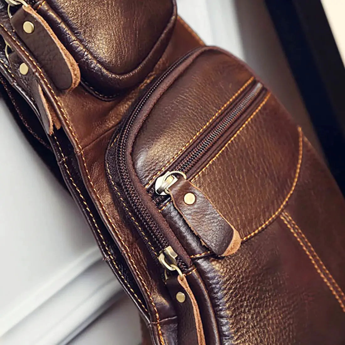 Men's genuine leather crossbody sling backpack in brown with zip pockets and brass hardware